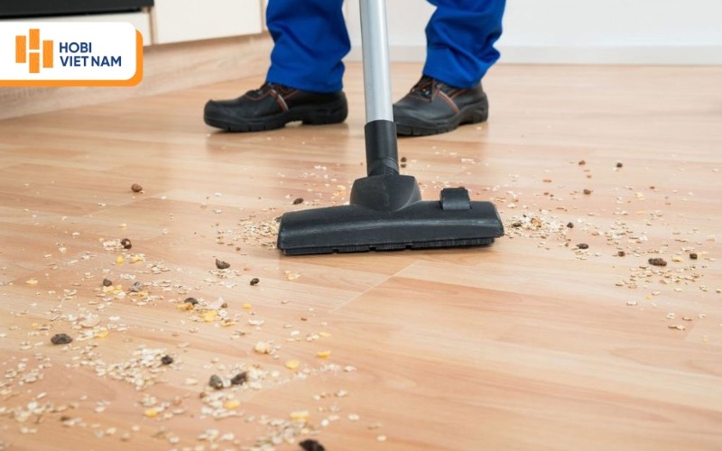 Dùng máy hút bụi để quét sạch bụi bẩn trên bề mặt sàn