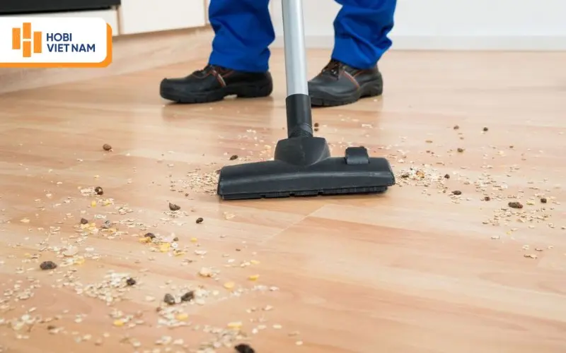 Dùng máy hút bụi để quét sạch bụi bẩn trên bề mặt sàn