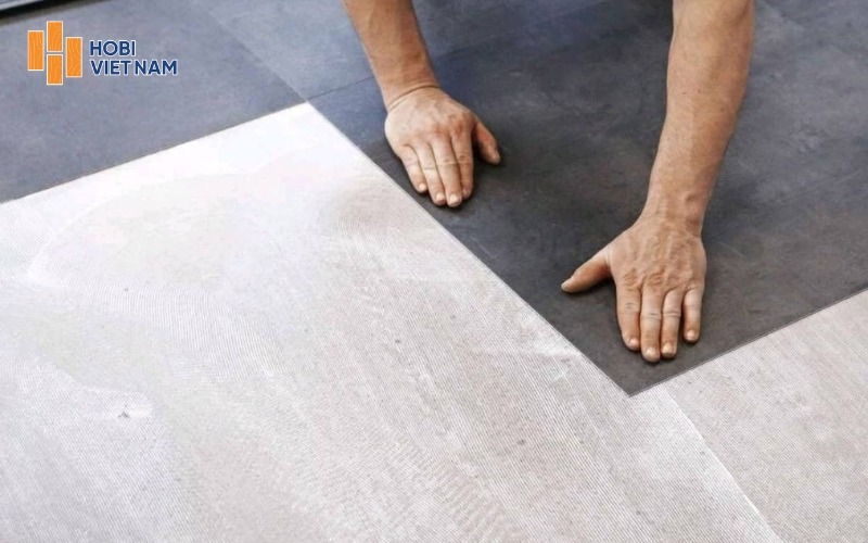 Đặt từng tấm sàn vào vị trí đã xác định, dùng lực ấn đều để bề mặt bám chắc