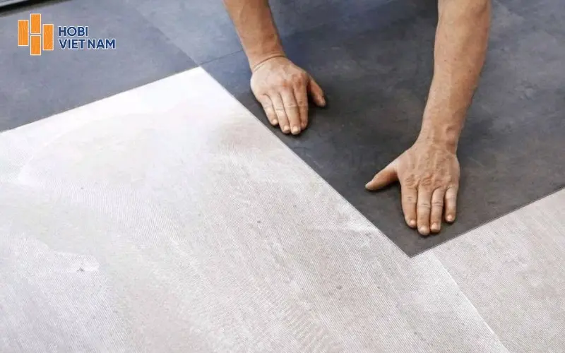 Đặt từng tấm sàn vào vị trí đã xác định, dùng lực ấn đều để bề mặt bám chắc