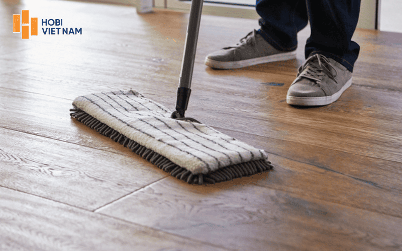 Sử dụng khăn ẩm đã vắt khô để vệ sinh bề mặt sàn nhựa giả gỗ dán keo